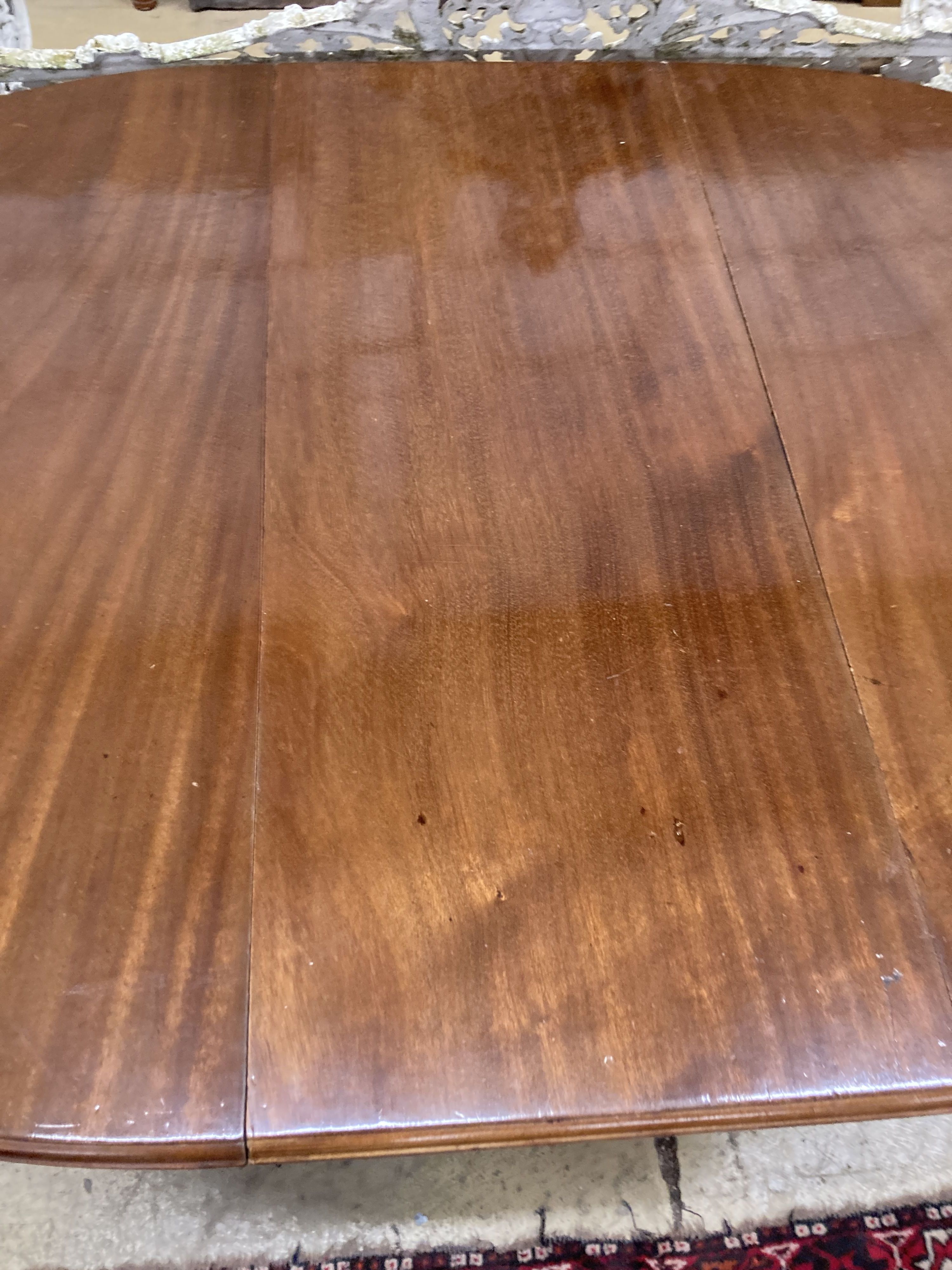 A 1930s mahogany oval topped extending dining table, one spare leaf, 174cm extended, width 106cm, height 73cm and winder